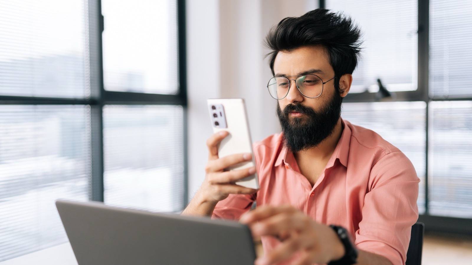 Young professional checking information on a phone at his desk