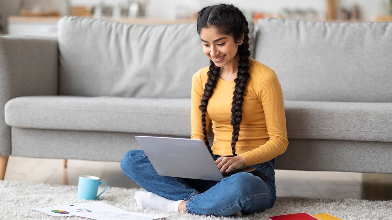 Woman working on a laptop with papers spread beside her