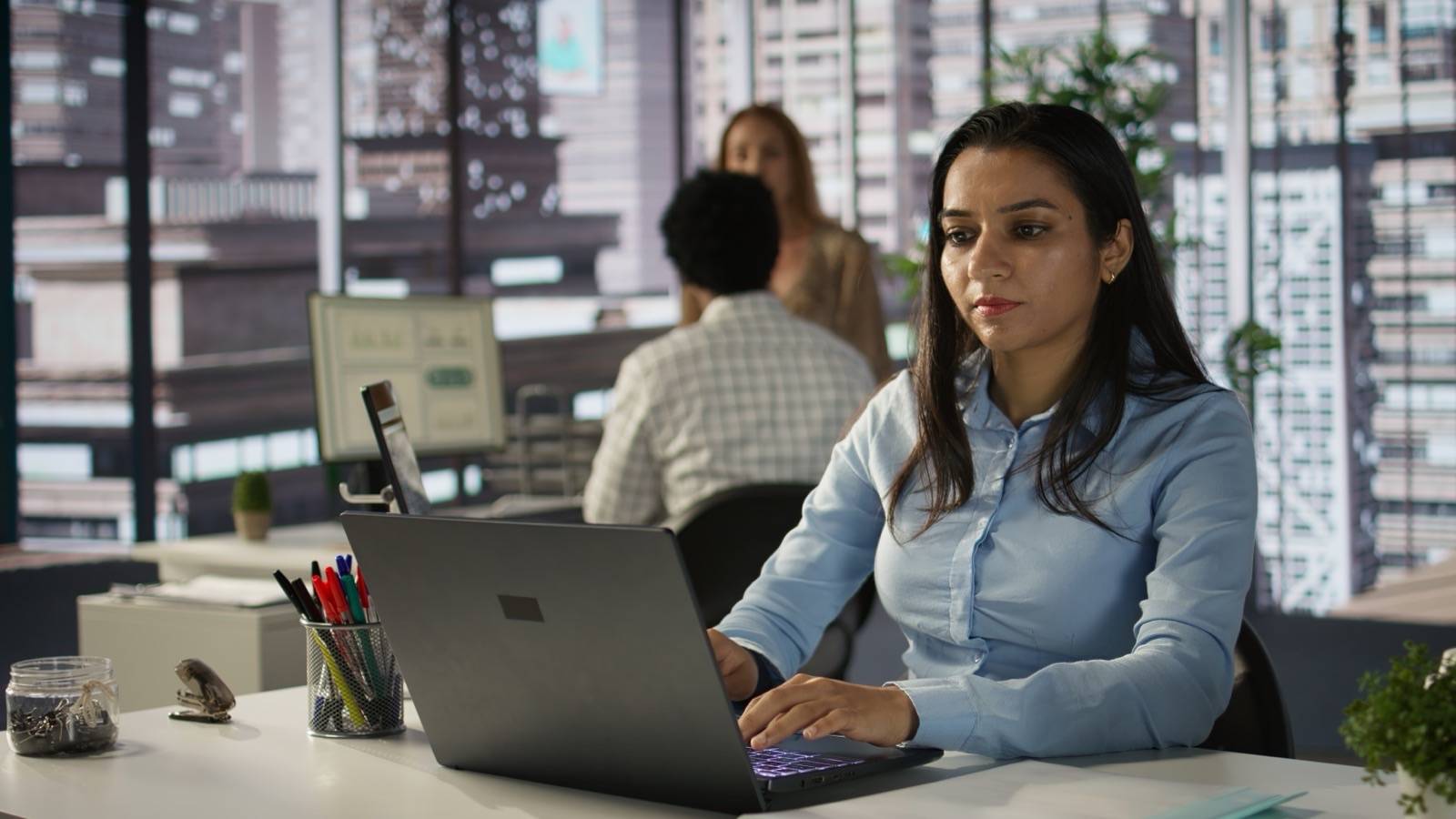 Office worker reviewing information on a laptop at her desk