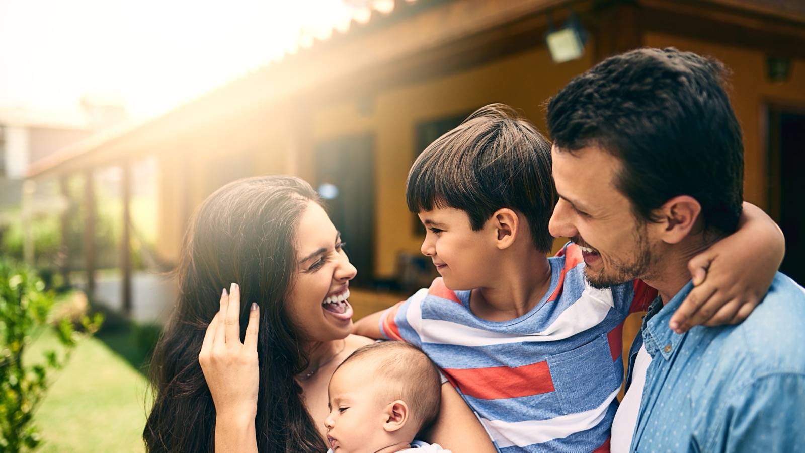 Young family with a baby and an older child outside their home