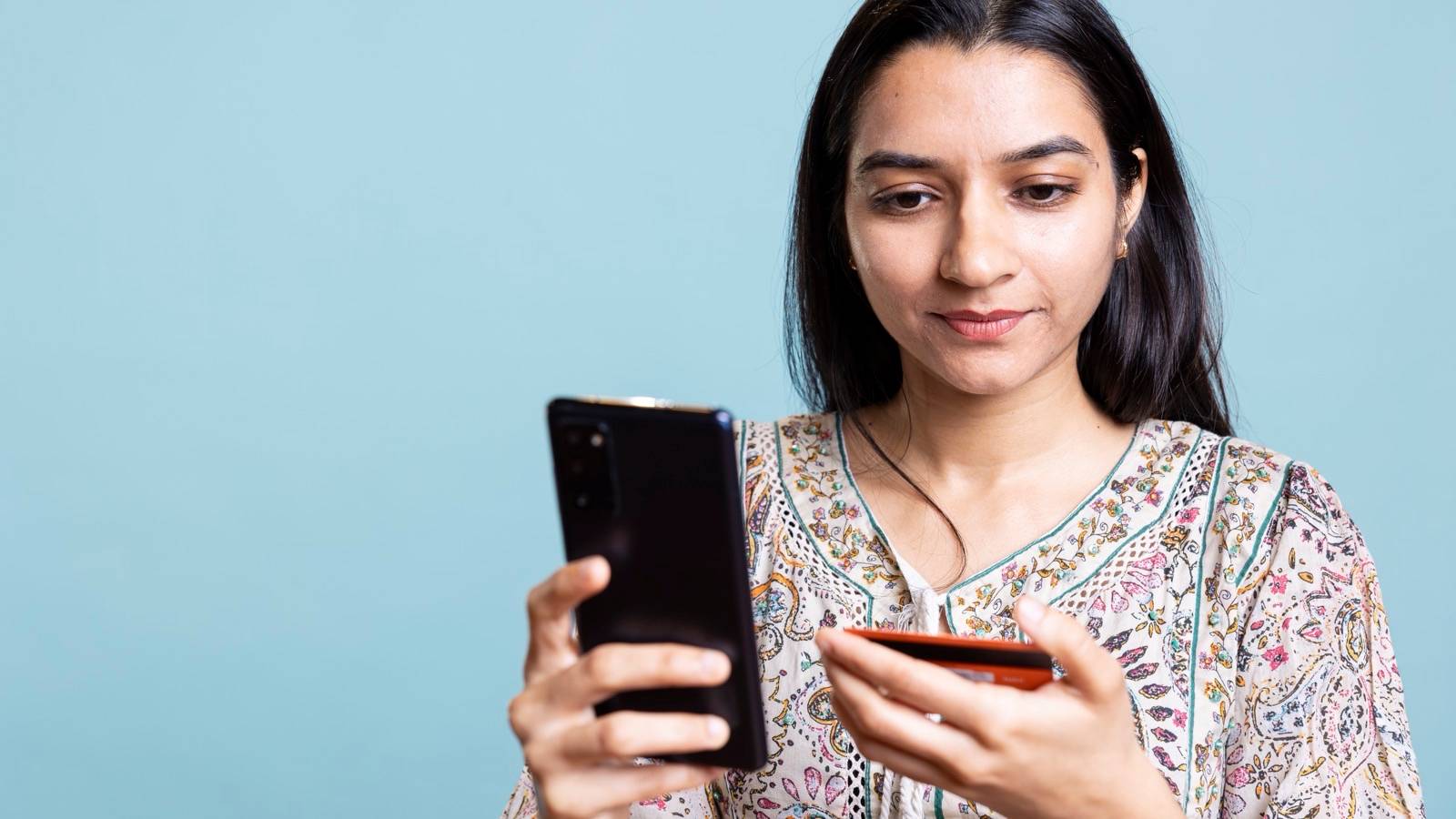 Woman checking her phone with a card in her hand